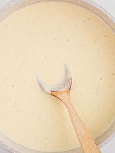 a wooden spoon in a bowl filled with batter and cheese sauce on a white surface