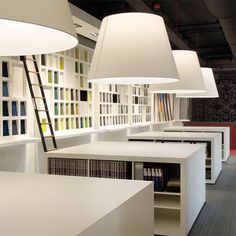 an office with white desks and hanging lamps