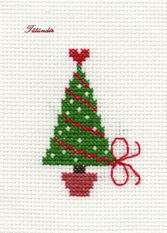 a cross stitch christmas tree with red ribbon