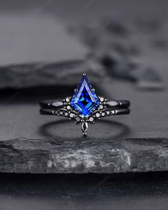 a blue diamond ring sitting on top of a rock