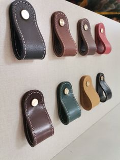 several different colored leather handles hanging on a wall