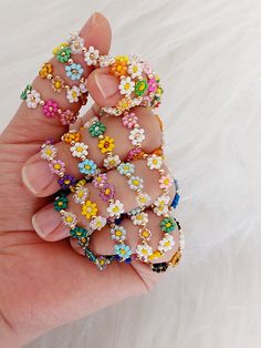 a woman's hand holding several colorful flower rings