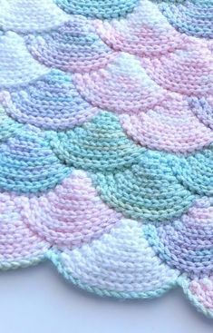 a crocheted blanket with pastel colors on the bottom and white, blue, green, pink, and purple circles