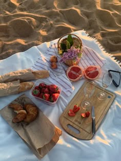 strawberries, oranges and other fruits are laid out on a blanket at the beach