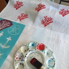 a white plate with red corals on it next to a blue and white table cloth