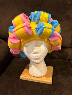 a white mannequin head with yellow and blue hair on it's head