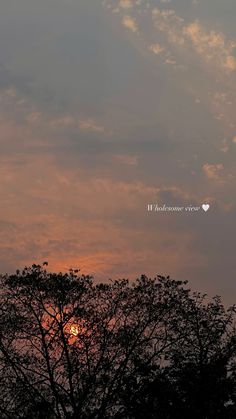 the sun is setting behind some trees with clouds in the sky and on top of it