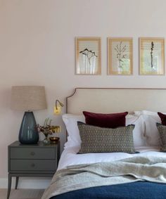 a bed with two lamps and pictures on the wall above it