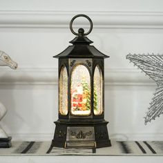 a small christmas lantern sitting on top of a table next to a white horse and snowflake