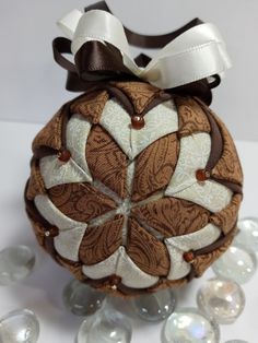 a brown and white ornament sitting on top of some glass beads with a bow