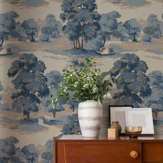 a wallpapered room with blue trees and white vases on top of a dresser