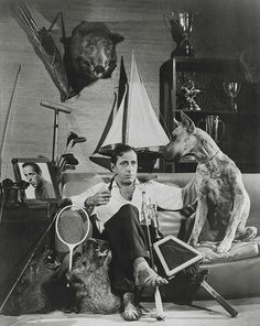 a man sitting on the floor with two dogs and tennis rackets in front of him