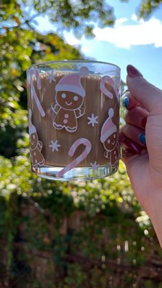 a person holding up a glass with some chocolate frosting on it in front of trees