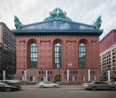 cars drive past a large building in the city