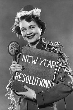 a woman holding a sign that says new year's resolutions, and smiling