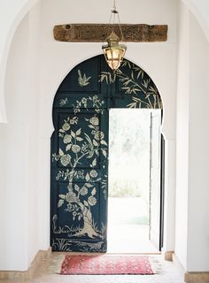 an open door with flowers painted on it and a rug in front of the doorway