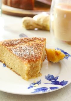 a piece of cake on a blue and white plate next to a glass of orange juice