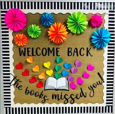 a bulletin board with colorful paper flowers and an open book on it that says, welcome back the books missed you