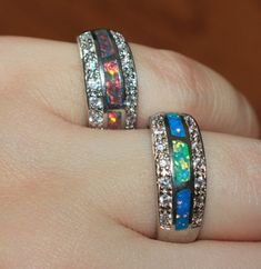 two rings with opal and white diamonds on top of each other's fingers