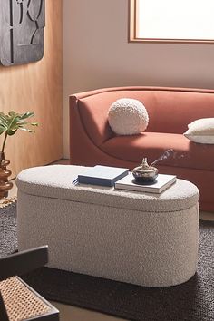 a living room with a couch, ottoman and coffee table in front of a window