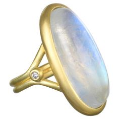 Considered to be a stone of inner growth and strength, this round rainbow moonstone with its two side diamonds has been set by designer Faye Kim in 18K gold* and reflects a bluish, milky light that has been compared to the light of the moon. The shape, polish, and matte gold finish enhances the moonstone's striking rainbow effect, and Kim’s modern design conveys understated elegance and a truly stylish, everyday look that is perfect for every occasion. *Faye Kim's signature 18K green gold is an Inner Growth, Contemporary Ring, Oval Rings, Moon Stone, Matte Gold, Rainbow Moonstone, Cocktail Rings, Green And Gold, Precious Metals