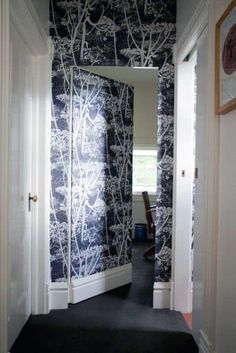 the hallway is decorated with black and white wallpaper, along with an open door