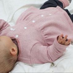 a baby laying on top of a white bed