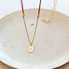 A very delicate necklace featuring double red thread strands, tiny golden nuggets on the sides, an oval simple shape pendant with a little piece of 14K gold fill chain on the bottom.The pendant is custom stamped with the letter of your choice. Please, type the letter you want to be stamped on your pendant at check-out!∙ Only 1 letter permitted.∙ We use only capital letters.In many cultures, the color red is traditionally used as a symbol of protection, good luck, or blessing. In my native Argent Dainty Oval Pendant Chain Necklace As Gift, Delicate Chain Necklace With Oval Pendant For Gift, Gift Oval Pendant Chain Necklace With Adjustable Chain, Oval Pendant Necklace With Delicate Chain As Gift, Delicate Oval Pendant Chain Necklace As Gift, Adjustable Chain Necklace With Oval Pendant, Gold Plated Chain Necklace With Oval Pendant, Gift Cable Chain Necklace With Oval Pendant, Red Gold Chain Necklace For Gifting