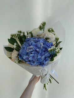 a bouquet of blue and white flowers being held by someone