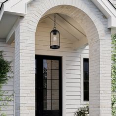 a white house with a black door and two planters on the front porch area