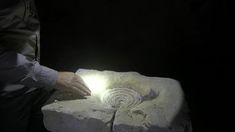 a man is working on a piece of stone with a light shining in the middle