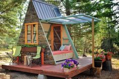 a small house built into the side of a wooded area with furniture and flowers on it