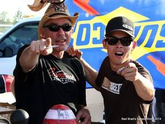 two men standing next to each other in front of a truck