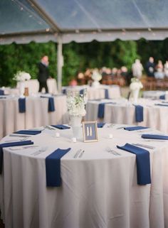 the table is set up with blue and white linens for an outdoor wedding reception