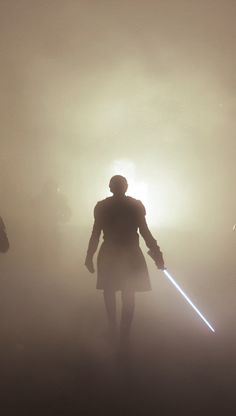 two people standing in the fog with lights on their backs and one person holding a light saber