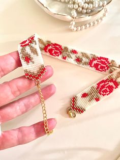 a hand is holding a beaded bracelet with beads and chains on it, next to a pearl necklace