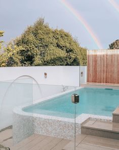 a pool with steps leading up to it and a rainbow in the background