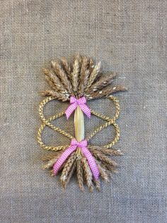 a bunch of wheat stalks with pink ribbon tied around them on a piece of fabric