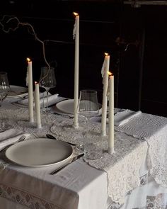 the table is set with white candles and place settings for two people to sit at