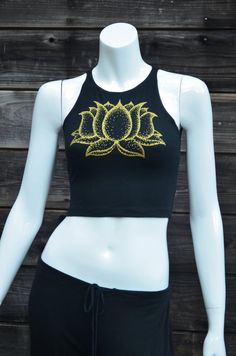 Gold Lotus Flower Fitted Crop Top - Women's Yoga Top - Festival Clothing This comfortable black fitted crop top features a double sided lotus flower design. The front has a large print in shinny metallic gold, and the back has a column of three smaller lotus flowers printed in glow in the dark. This Lotus flower is an original hand drawn image. The dark image shows the tank under a blacklight that is charging the glow in the dark ink.95% Cotton / 5% SpandexMade in the USAAvailable in sizes:SMALL Black Cropped Crop Top For Yoga, Fitted Halter Crop Top For Yoga, Fitted Cropped Top For Yoga, Spring Cotton Crop Top For Yoga, Fitted Cotton Tank Top For Festival, Fitted Cotton Tank Top For Festivals, Cotton Cropped Top For Yoga, Spring Black Crop Top For Yoga, Spring Fitted Yoga Tops