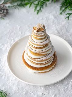 a white plate topped with a stack of pancakes covered in icing and powdered sugar