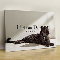 a leopard laying on the floor in front of a christian dior sign that reads paris