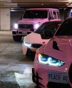 three pink sports cars are parked in a parking garage with their lights on and the hoods down