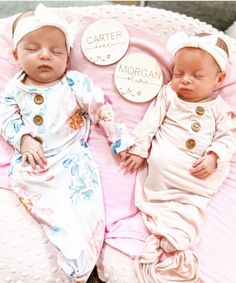 two baby babies laying next to each other on top of a pink blanket covered in buttons