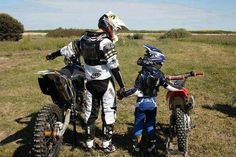 a man on a dirt bike with two small children standing next to him and holding hands