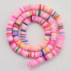 multicolored beads are arranged on a white surface with a string in the middle