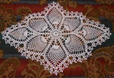 a white doily sitting on top of a red and black table cloth with an ornate design