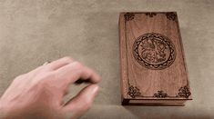 a hand holding a mouse next to a wooden box with a dragon design on it