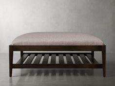 a wooden bench sitting on top of a gray floor next to a white and grey wall