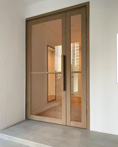 an empty room with two glass doors on the wall and one door opened to reveal another room